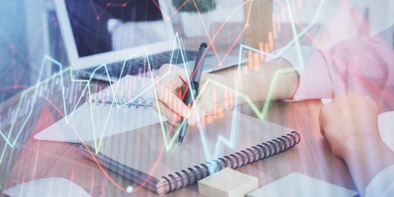 Financial charts displayed on woman's hand taking notes background. Concept of research. Double exposure